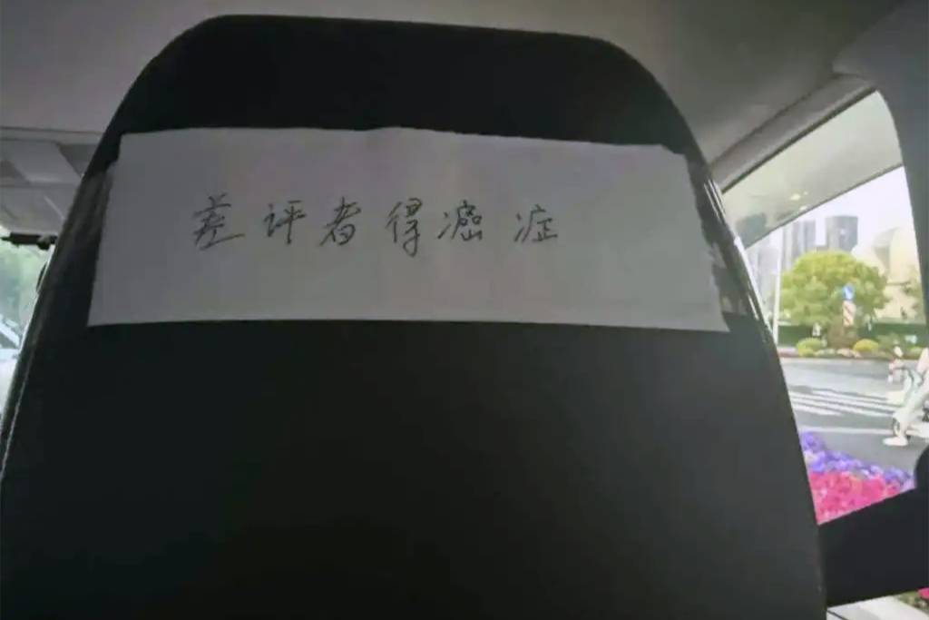 網(wǎng)約車(chē)椅背粘貼詛咒貼紙，內(nèi)容為：差評(píng)者得癌癥